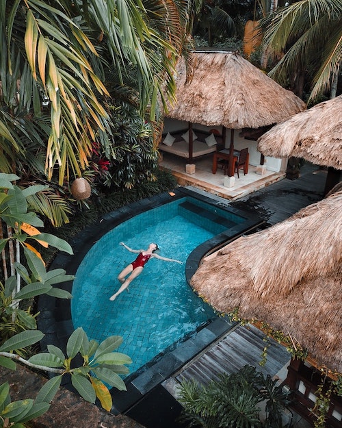 Photographie d'une piscine au milieu des palmiers