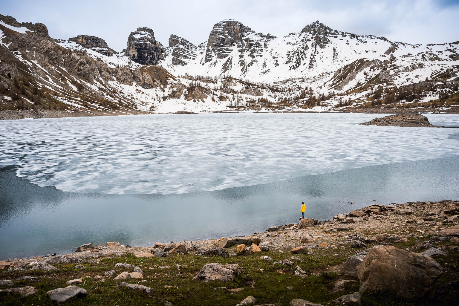 Femme devant le lac d'allos partiellement gelé