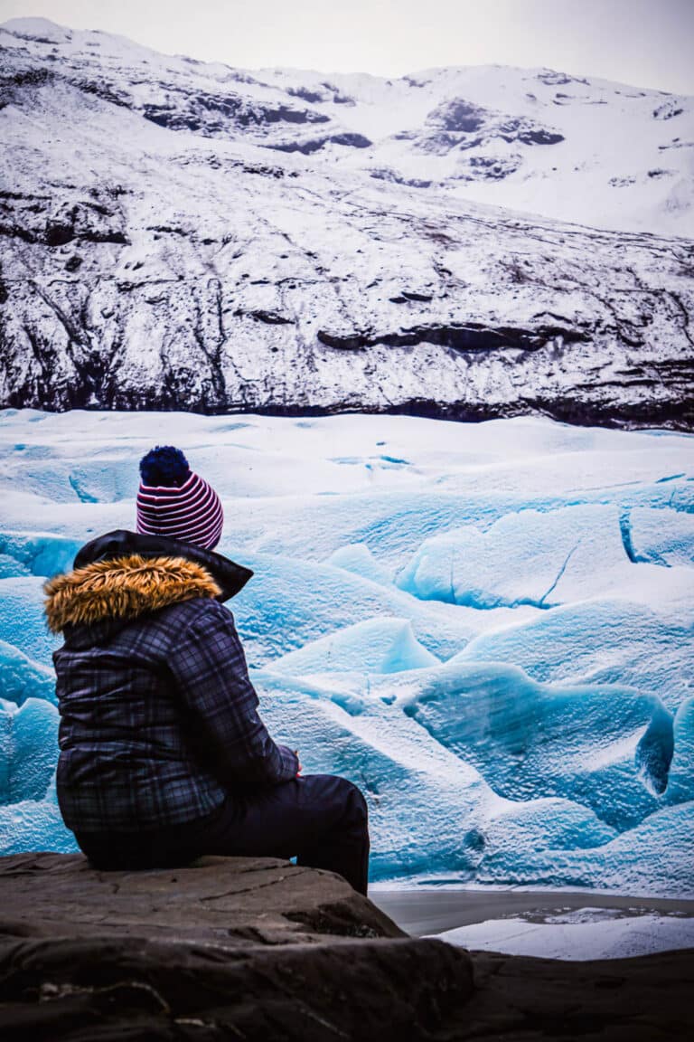 Photo d'une personne assise face au glacier Svínafellsjökull