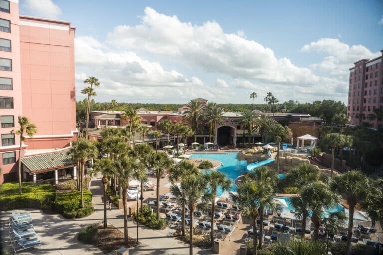 Vue sur la piscine du Caribe Royale Orlando avec palmiers, transats et bâtiments de l’hôtel en Floride.